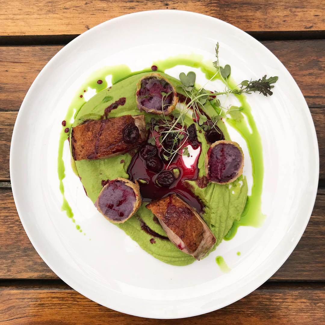 Danie z zielonym sosem i świeżymi ziołami na białym talerzu